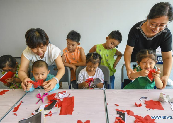 Folk Artists Instruct Children to Do Paper Cutting in Hebei